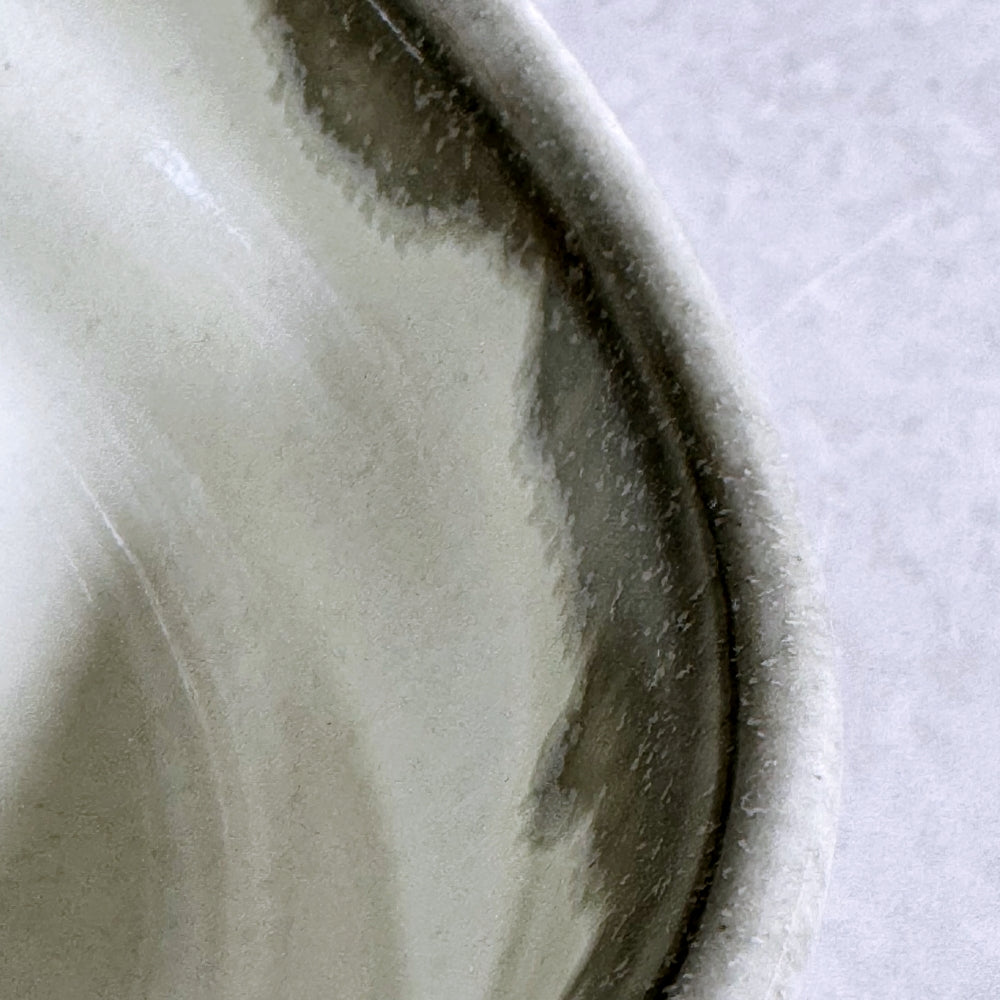 Close-up of a ceramic matcha bowl with a subtle pattern on a light background