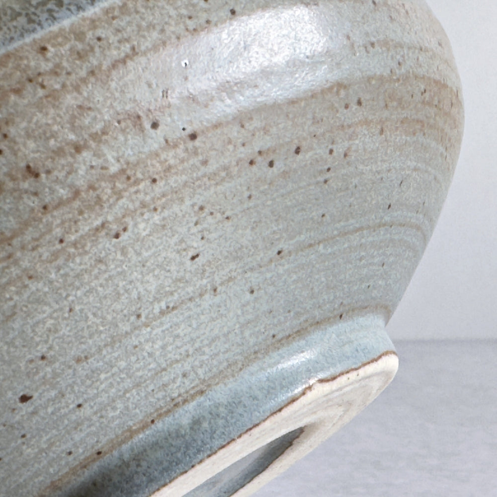 Close-up of a ceramic matcha bowl with a textured surface on a light grey background
