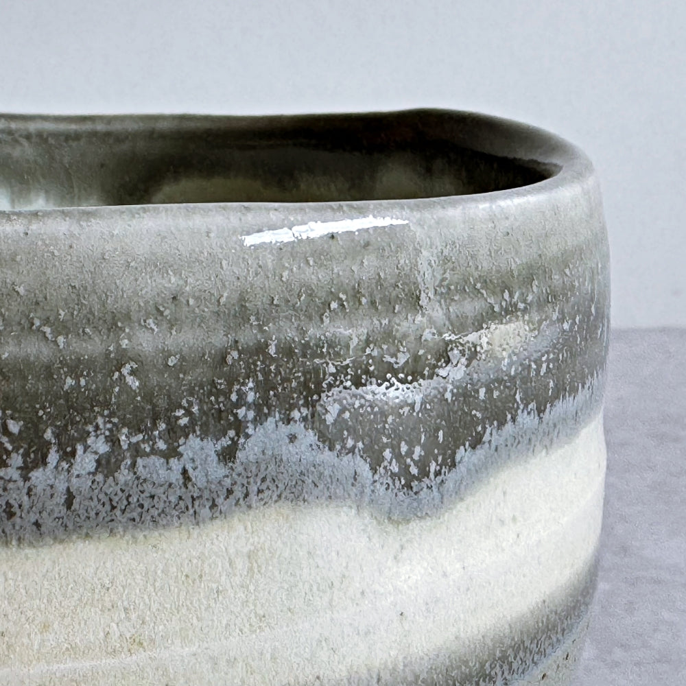 Close-up of a  rim of ceramic matcha bowl with a textured surface on a light gray background