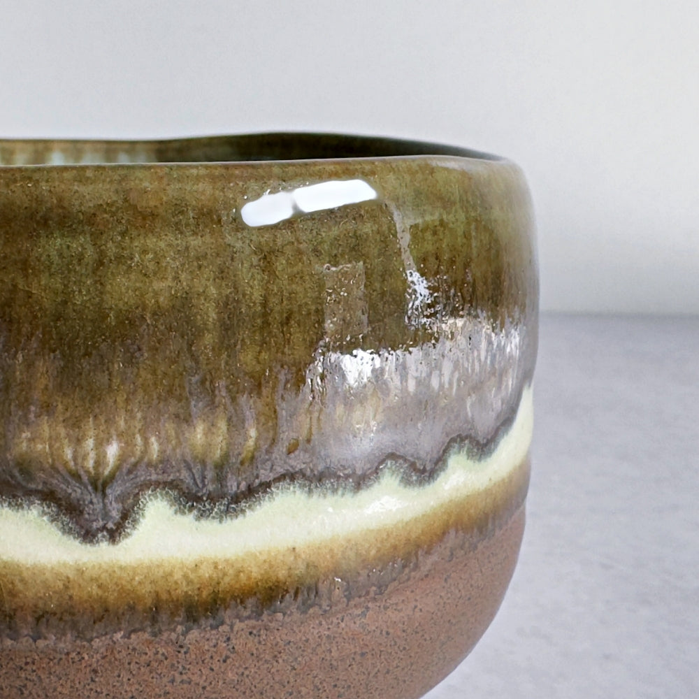 Close-up of a ceramic matcha bowl with a gradient glaze on a light background