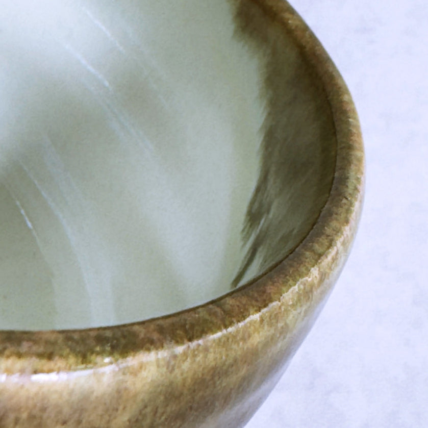 Close-up of a Japanese ceramic matcha bowl with a textured rim on a white background